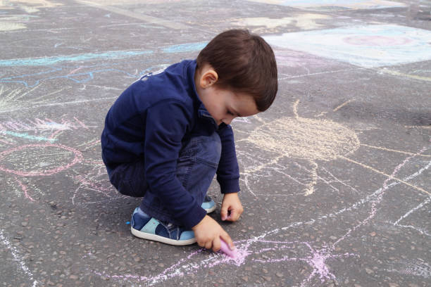 istock A little boy draws with chalk on the pavement 1412726129