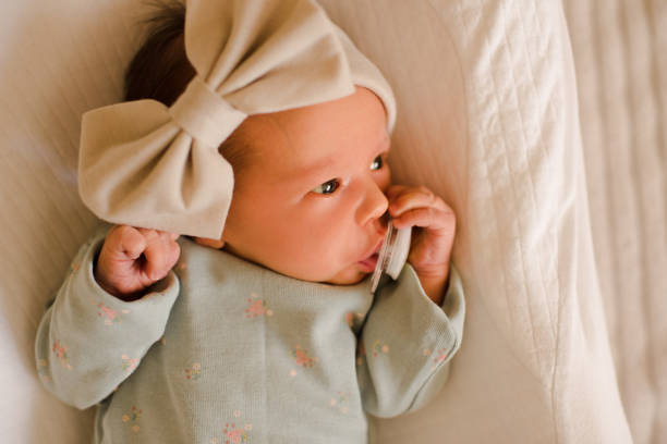 petite fille élégante avec tétine au lit - baby people headband portrait photos et images de collection