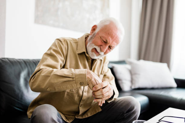 istock Senior man rubbing his hands in discomfort, suffering from arthritis in his hand while sitting on sofa at home. Elderly and health issues concept, Pain in the hands can be symptoms of carpal tunnel 1412728866
