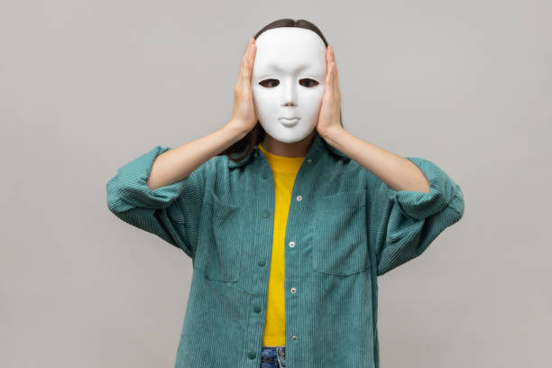 istock Unknown woman holding white mask, standing covering face, multiple personality disorder. 1412730078