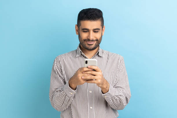 istock Businessman using cellphone and smiling, reading good news message, enjoying mobile application. 1412730143