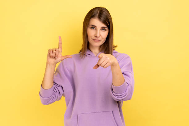 istock Young woman showing looser gesture and pointing at camera, looking with grumpy face. 1412732914