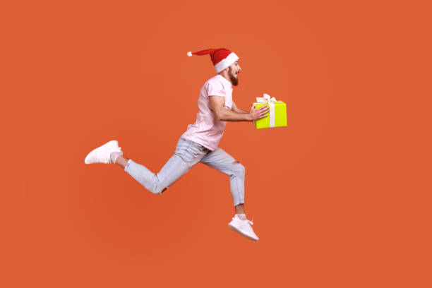 istock Man jumping in air or running quickly fast to give present box for Christmas, expressing happiness. 1412732982