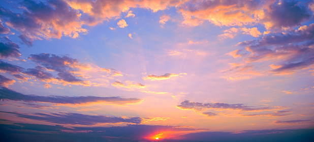 Fantastic pink sunset against bright blue sky with fluffy clouds.