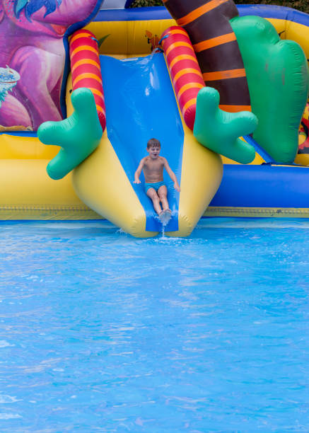 istock Boy has into pool after going down water slide during summer. little boy sliding down water slide and having fun 1412736860