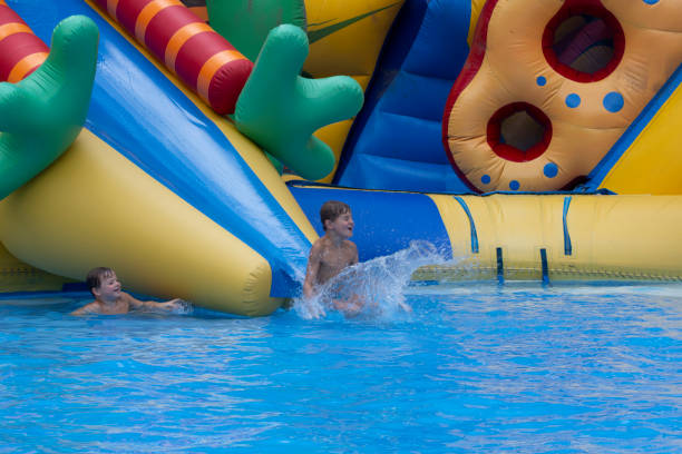 istock Boy has into pool after going down water slide during summer. little boy sliding down water slide and having fun 1412736929