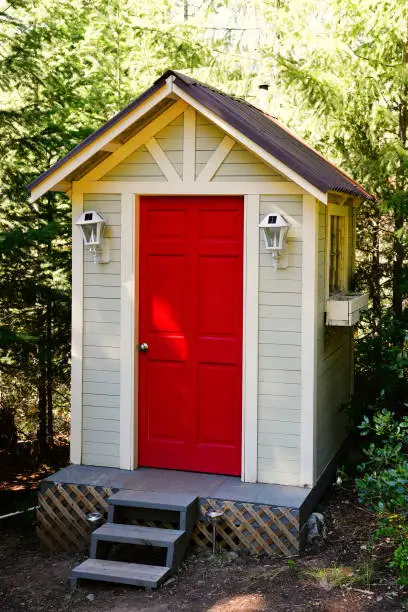An image of an outdoor composting toilet with bright red door.