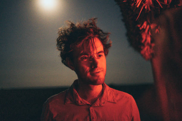 Portrait of young man below thatched hut, red light