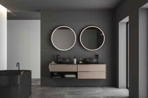istock Dark bathroom interior with concrete floor, black bathtub and oval mirrors, double sink, side view. 1412742858