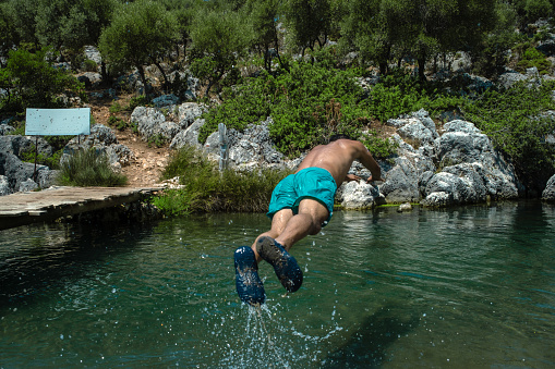 Spring water in nature. Model running and jumping into the water. Nature area, active lifestyle with high vitality