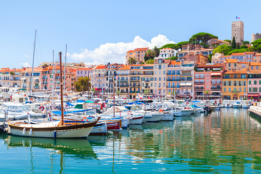 Cannes marina view on a sunny summer day, coastal landscape with moored yachts and colorful houses on a background. France