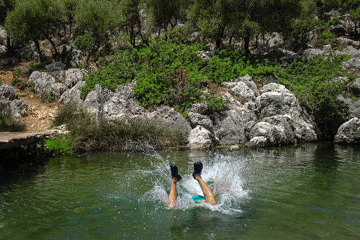 Spring water in nature. Model running and jumping into the water. Nature area, active lifestyle with high vitality