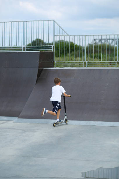 istock Active boy riding a scooter in skate park 1412746402