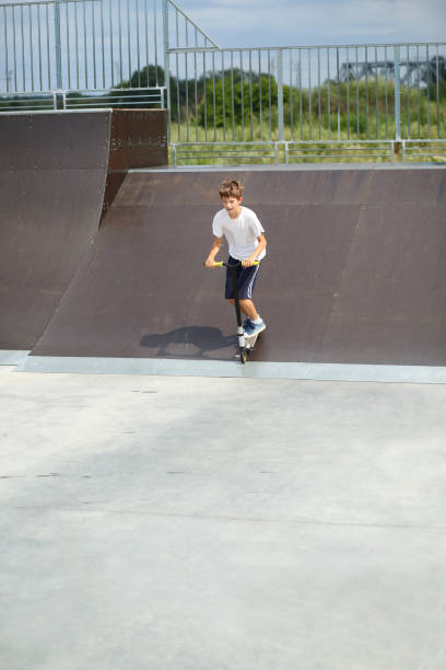 istock Active boy riding a scooter in skate park 1412746403