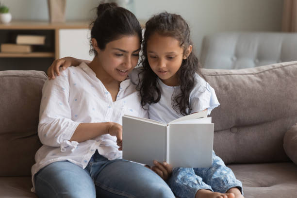 istock Happy young Indian mom teaching little daughter to read book 1412746831