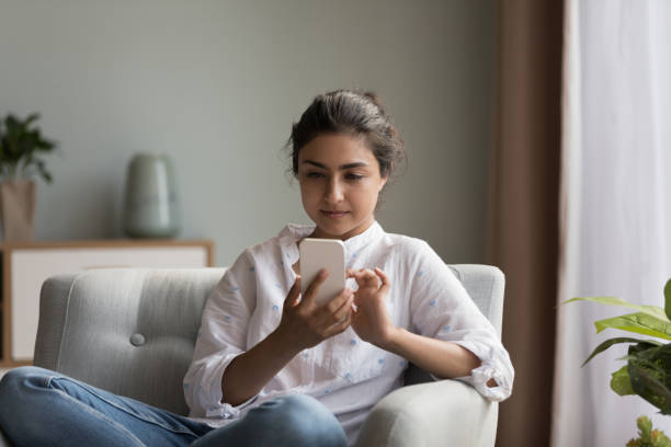 Focused beautiful Indian smartphone user woman texting message