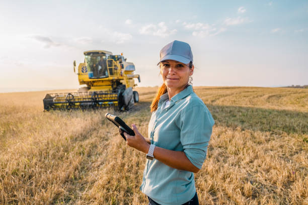 una agricultora sostiene una tableta digital en un campo agrícola. agricultura inteligente - patrones de vestimenta campesina fotografías e imágenes de stock