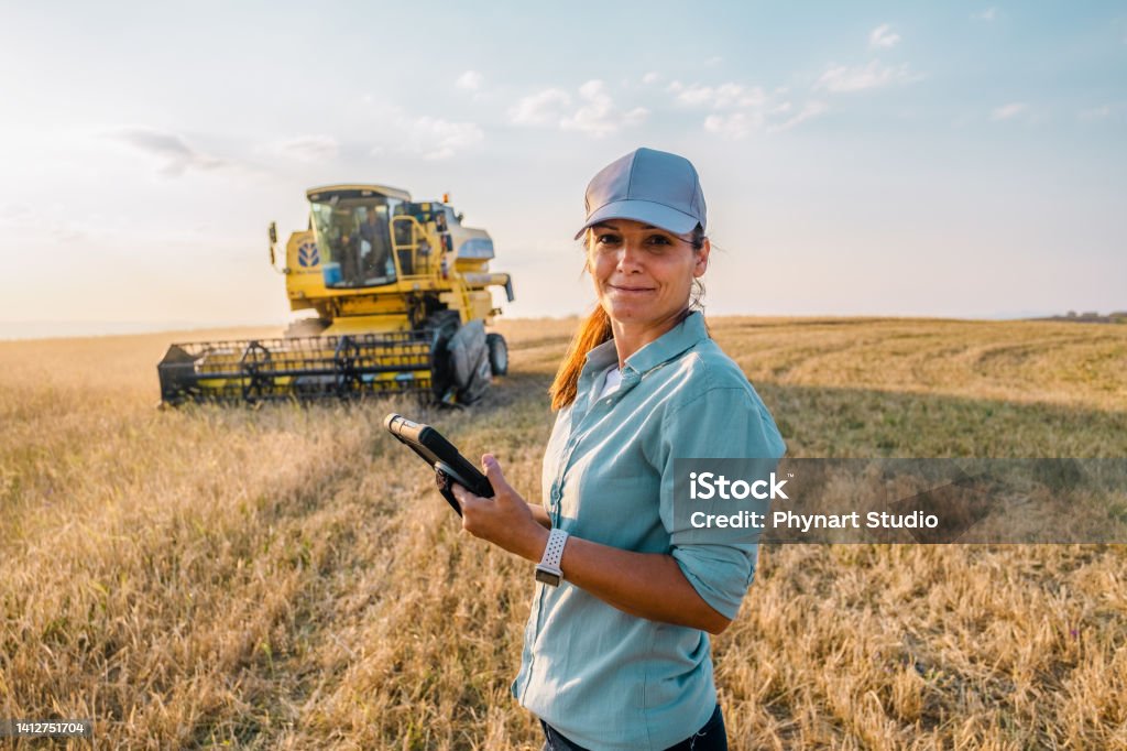 Female Farmer is Holding a Digital Tablet in a Farm Field. Smart Farming Farmer Stock Photo