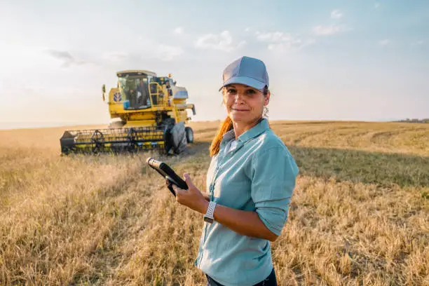 Photo of Female Farmer is Holding a Digital Tablet in a Farm Field. Smart Farming