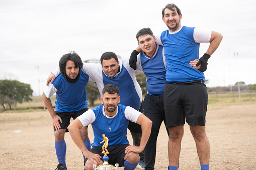 Portrait of mentally disabled soccer players with a trophy at field