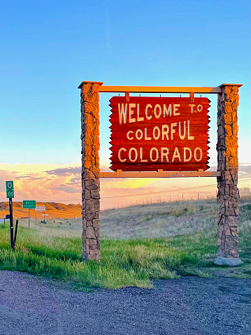 Weld County, Colorado, USA - July 8, 2022: An iconic “Welcome to Colorful Colorado” sign greets travelers on Interstate 25 heading south at the border between Wyoming and Colorado at sunset.
