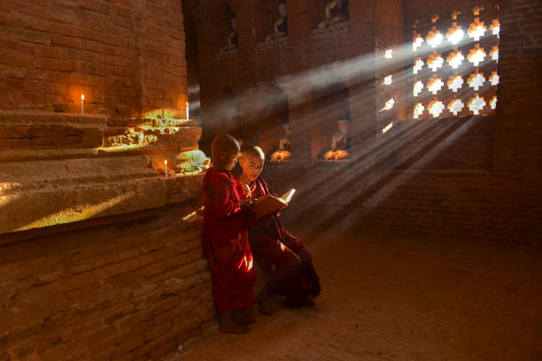 Two young buddhist monks praying inside the temple in Bagan, Myanmar