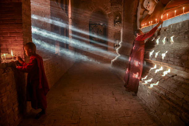 Two young buddhist monks praying inside the temple in Bagan, Myanmar