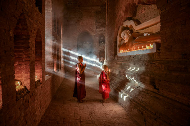 Two young buddhist monks praying inside the temple in Bagan, Myanmar