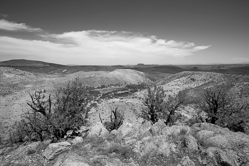 Desert landscape, with small, dry water tank in a tree area, Tunoco Mountain in the background