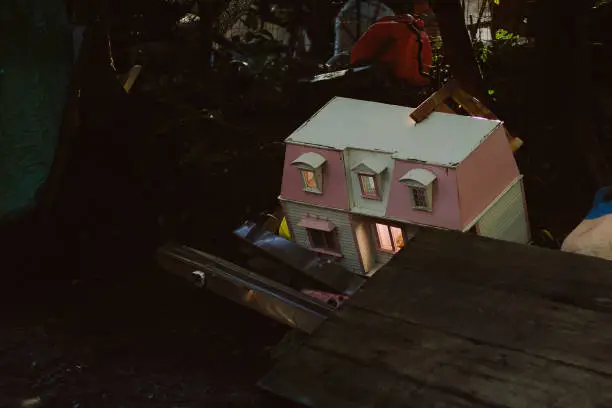 Photo of Children's doll house lit up in a garbage pile