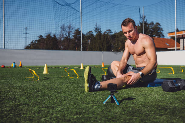 Shirtless athlete stretching outdoors sitting on the ground