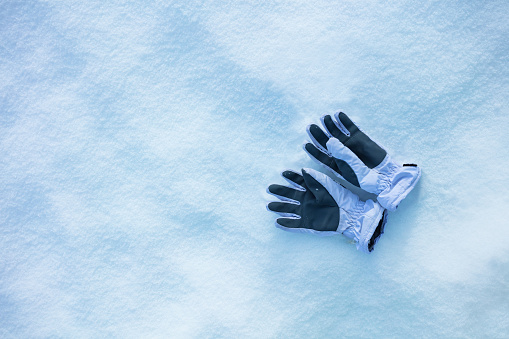 White sport gloves in the snow, clean view from above, winter holidays concept