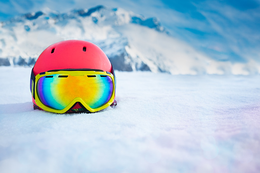 Pink beautiful helmet with ski mask in snow over mountain range on background