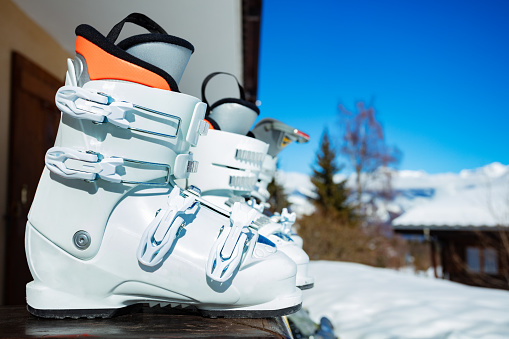 Close-up of alpine ski boots on the balcony rail - mountain winter vacation concept