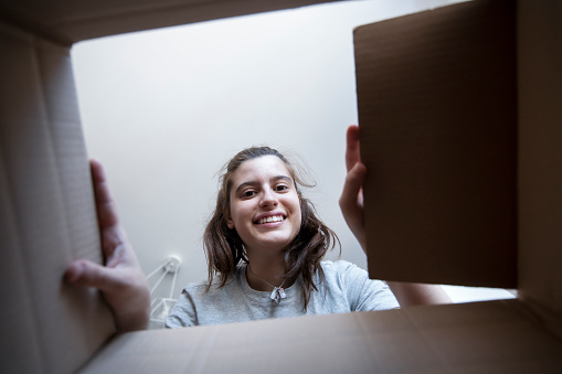 Smiling  young woman opening a delivered carton box.