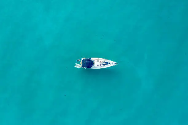 Centered areal view of a Bavaria50 on anchor in clear blue water