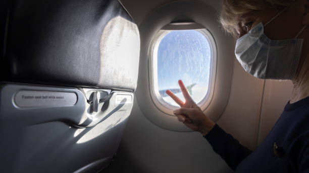 istock Posing for camera in airplane. Mature women posing for camera in airplane, during long flight. 1412778961