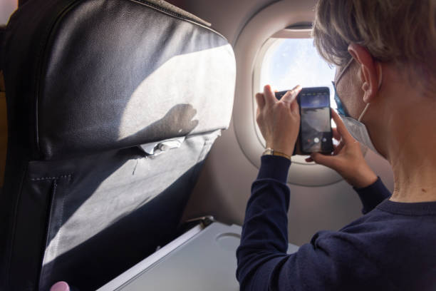 istock Making video from airplane window. Mature women making video from the window during the flight. 1412778971