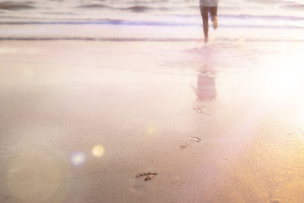 Young woman walking on the sand and leaves footprints