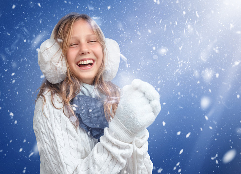 Girl in a sweater and gloves in snowflakes in winter