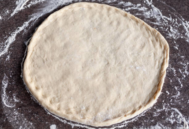istock Rolled out pizza dough on floured slate surface, photographed overhead 1412781385