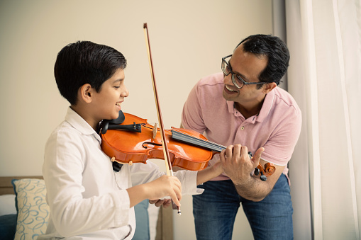 Father teaching son to play violin