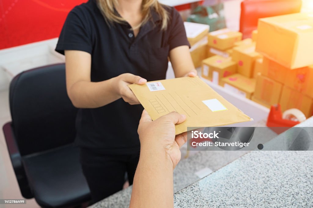 Male hand send mail envelope to the female of post office before sending . Mail Stock Photo