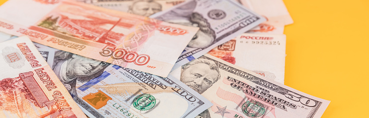 One hundred rubles lying on american dollars as a symbol of weakness russian national currency and strengthening of american dollar.