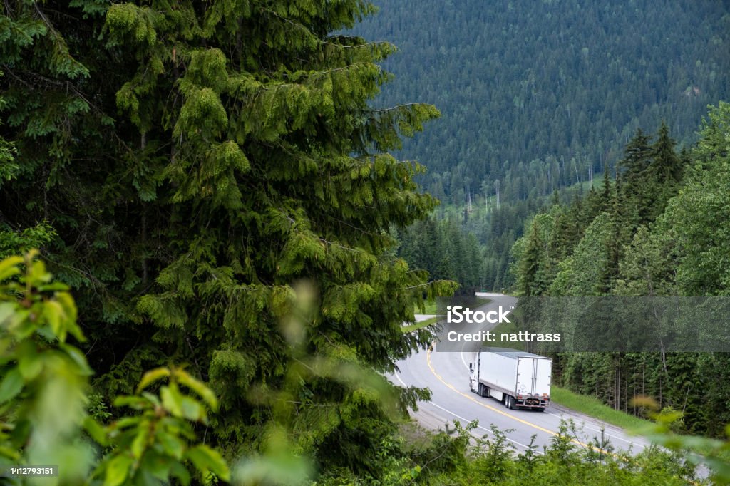 Container truck along a scenic road through the Canadian Rockies Large container truck driving along a highway. Lush forests while driving along the Trans Canadian Highway in British Columbia, Canada. Truck Stock Photo