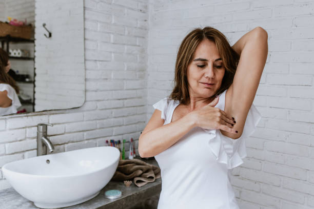 istock Hispanic senior middle aged woman after shower using antiperspirant or deodorant after bath at home and taking care of armpit skin do daily beauty treatment in bathroom in Latin America 1412793213