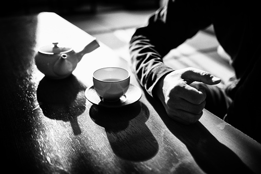 Image of man having tea time with Japanese teapot and cup