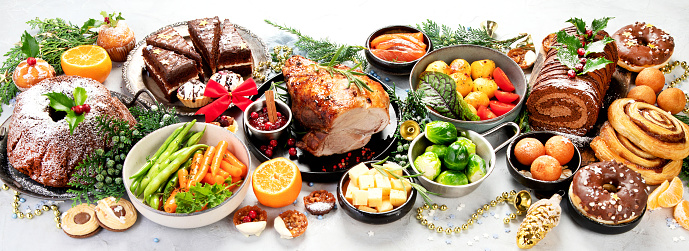 Delicious Christmas themed dinner table with roasted meat, potato, appetizers and desserts. Holiday concept. Top view on a grey background. Holiday concept. Panorama.
