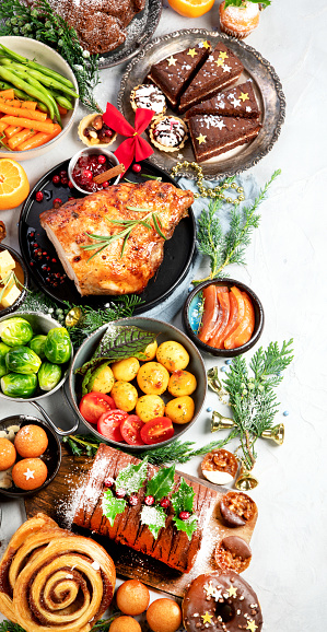 Delicious Christmas themed dinner table with roasted meat, potato, appetizers and desserts. Holiday concept. Top view on a grey background. Holiday concept.