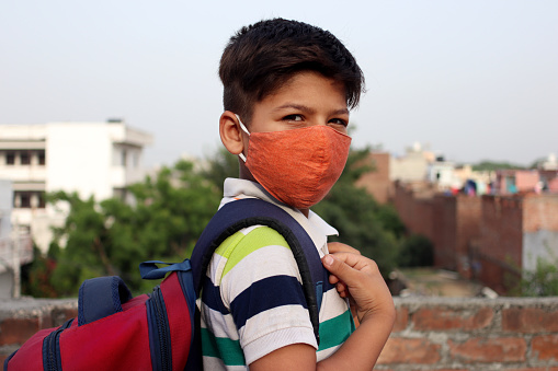 8-9 years schoolboy covering his face with face mask for protection from COVID-19 or Coronavirus.